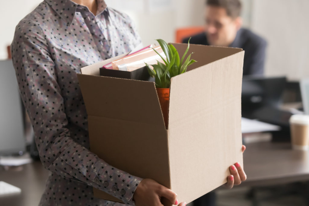 person carries box of personal belongings out of office
